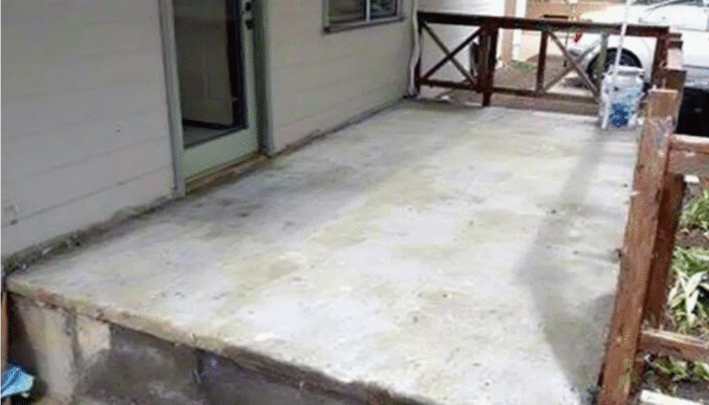 The image depicts a concrete front porch area of a red brick ranch house, showcasing potential for updates and improvements. The space is inviting and offers a blank canvas for simple updates to enhance curb appeal, with features like garage doors and a front door that could benefit from a fresh exterior makeover.