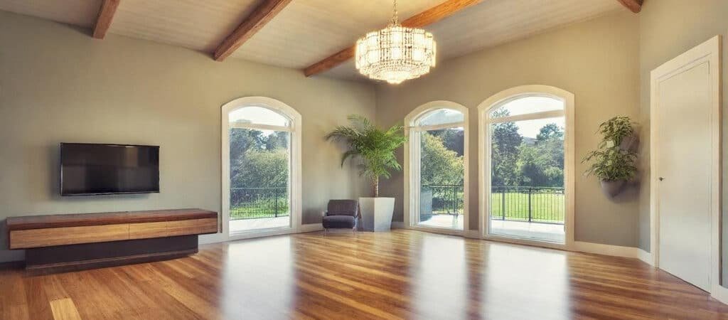 Spacious raised ranch finished basement with warm, natural daylight, featuring modern decor, rich hardwood tones, and expansive windows, captured in ultra-realistic HDR photography with subtle shadows